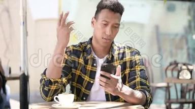 非洲青年男子在智能手机、室外咖啡厅失物招领